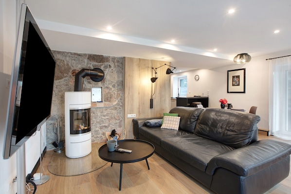 A modern living room with a stone accent wall, a fireplace, a leather sofa, and a flat-screen TV.
