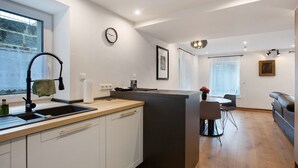 Una cocina moderna con una isla integrada, una zona de comedor con mesa y sillas, un sofá y un ventanal con vistas.