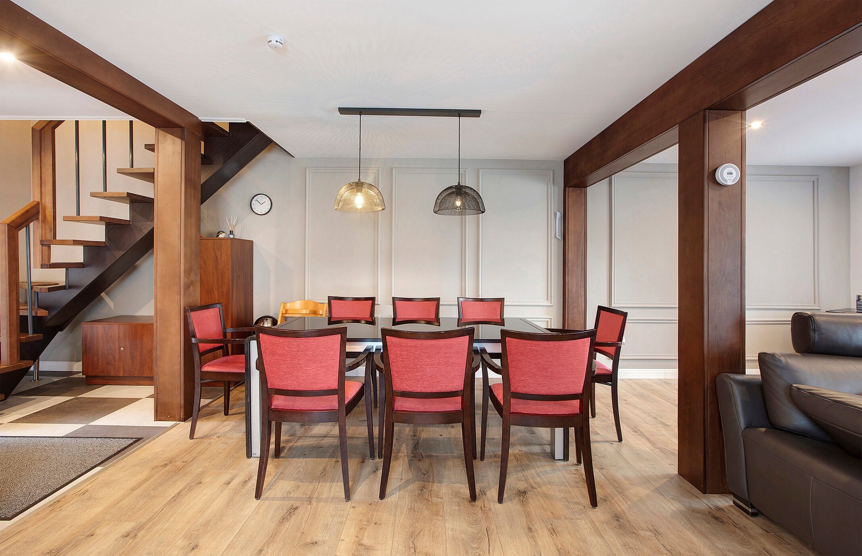 Un comedor con una mesa y sillas de madera, una escalera y una sala de estar con sofá.