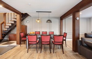 Un comedor con una mesa y sillas de madera, una escalera y una sala de estar con sofá.