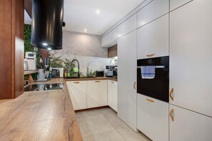A modern kitchen with white cabinets, a wooden countertop, and a built-in oven.