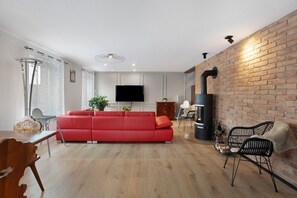 Un salon moderne avec un canapé rouge, un plancher en bois, un téléviseur et un mur en briques.