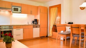 Une cuisine dotée de meubles en bois, d’un four à micro-ondes, d’une machine à café et d’un coin repas avec une table et des chaises.