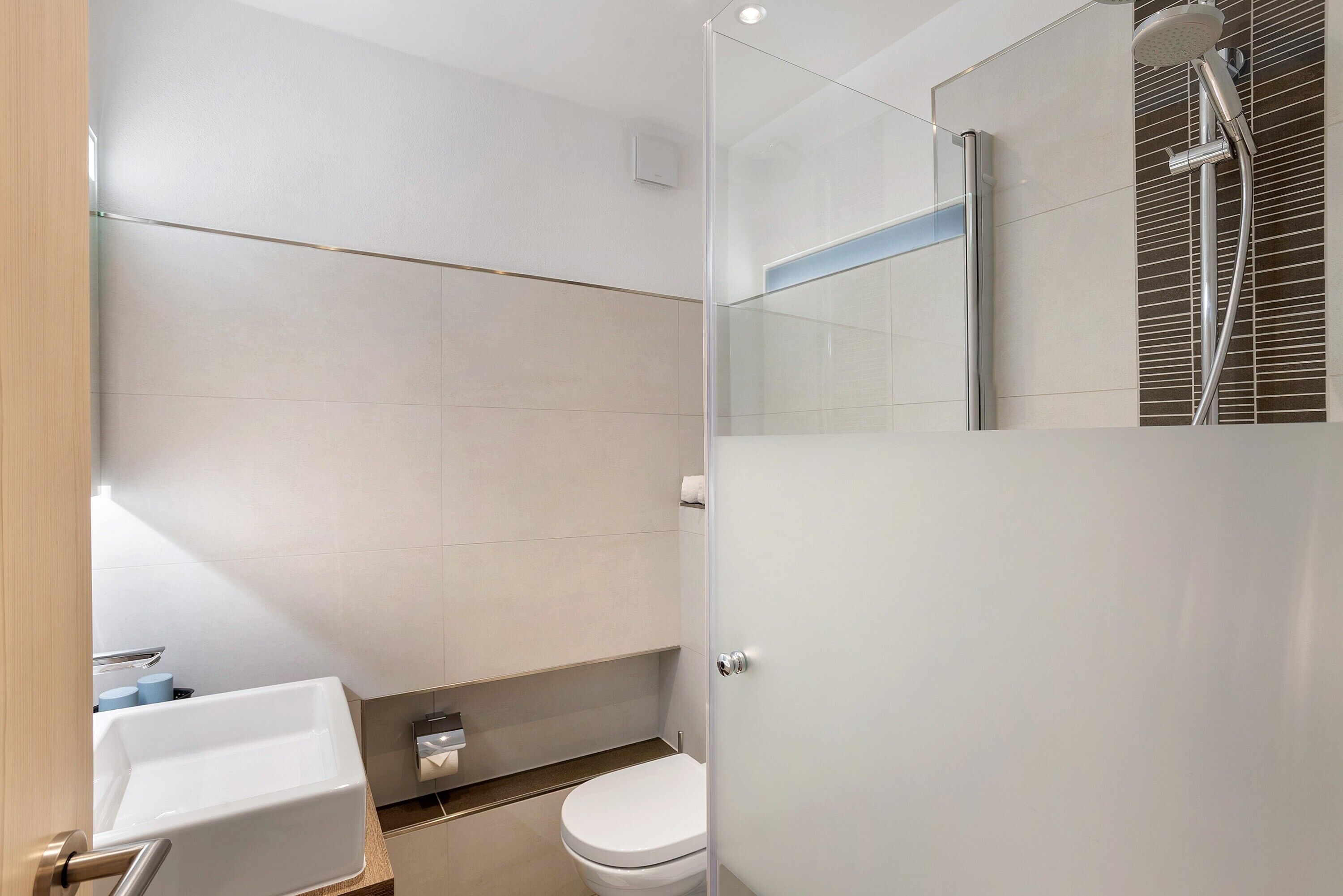 A modern bathroom with a shower, toilet, and sink.