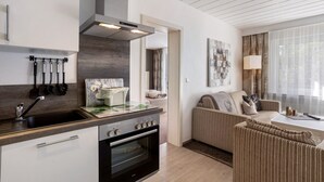 Una cocina moderna con horno empotrado, un lavaplatos y una estufa. Hay una zona de comedor con un sofá y una mesa.