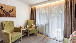 A room with two green armchairs, a small round table, a painting of a deer, and a large window with sheer curtains. - Apartment 'Typ 2' with Shared Garden, Balcony and Wi-Fi (Willingen (Upland))