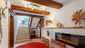 A staircase leading to a second floor, a fireplace with a TV, and a red carpet. - Apartment 'Typ 2' with Shared Garden, Balcony and Wi-Fi (Willingen (Upland))