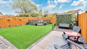 A backyard with a well-maintained lawn, a wooden fence, and outdoor furniture including a table and chairs. - Bright and modern 2 bed flat with parking and a garden you can relax in (Edinburgh)