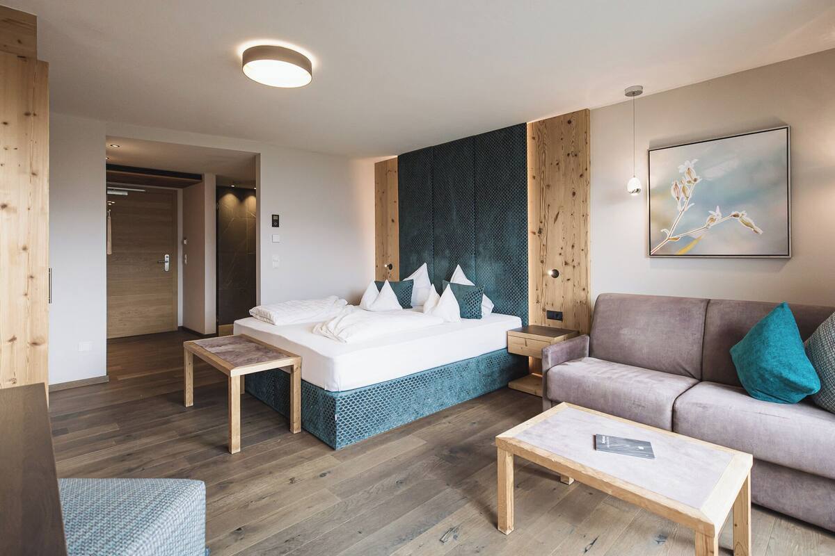 Een moderne hotelkamer met een bed, een bank, een bijzettafeltje en een schilderij aan de muur.