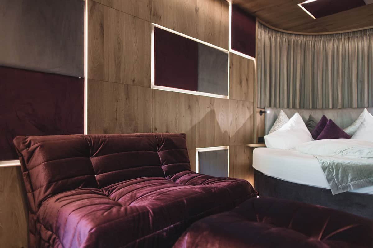 Een moderne slaapkamer met een groot bed, een slaapbank en een aan de muur bevestigde televisie.