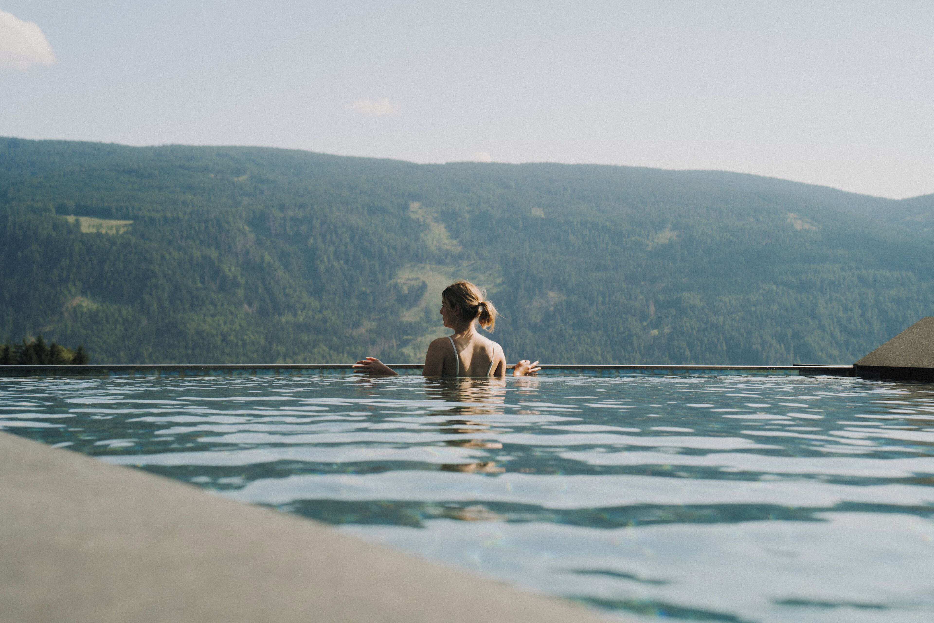 A person in a swimming pool with a mountainous landscape in the background.