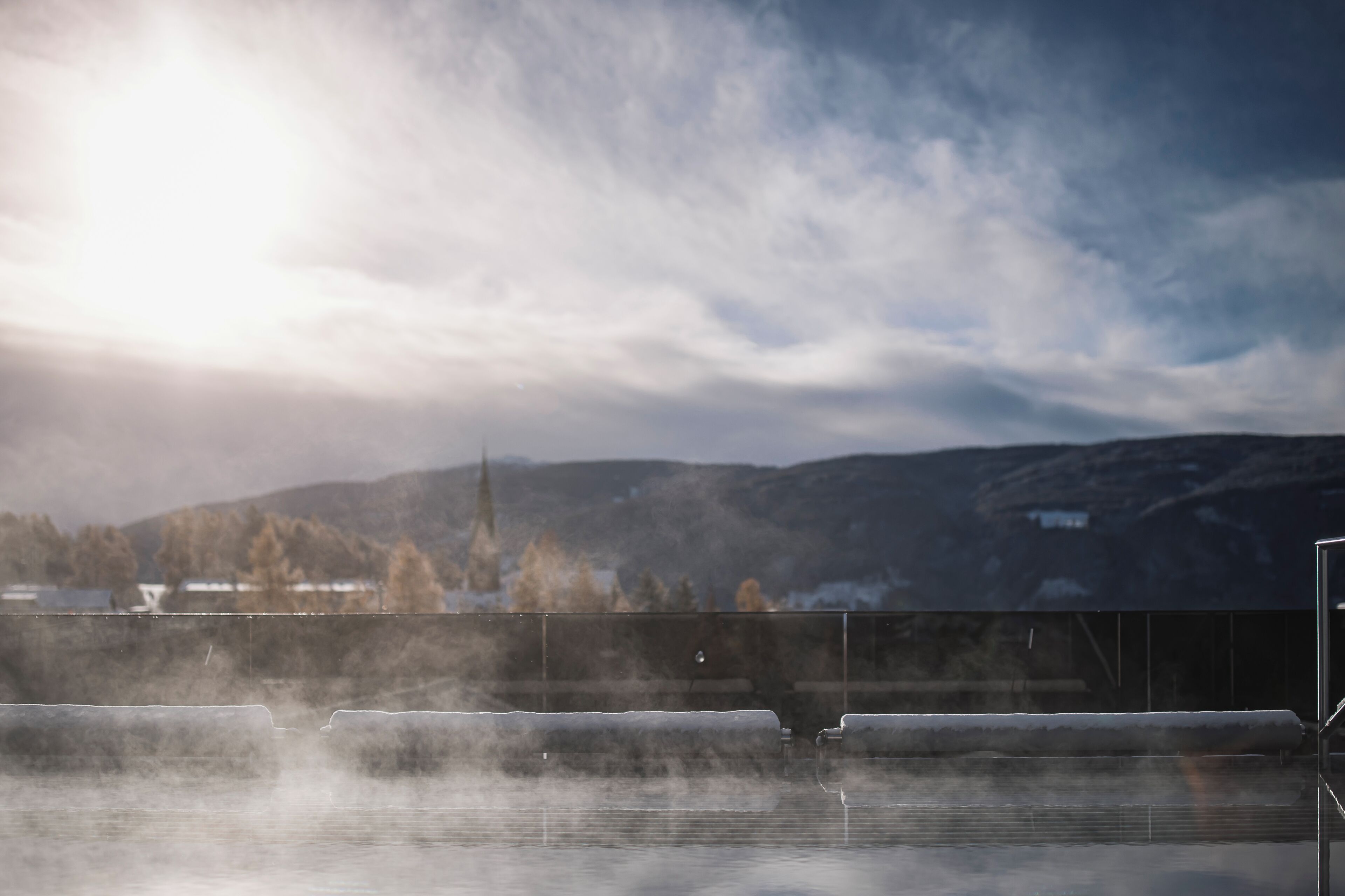 A steam room with a view of mountains and a cloudy sky.