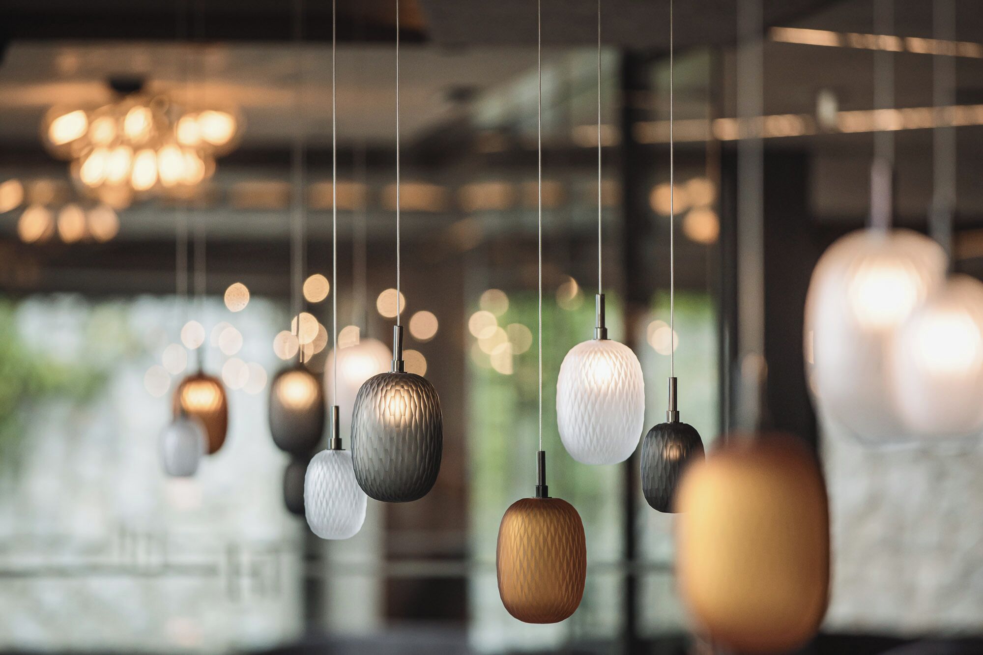 A series of pendant lights with a textured design, hanging from a ceiling in a well-lit indoor space.