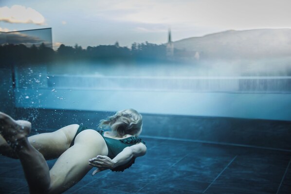 Una persona nadando en una piscina con una cascada al fondo.