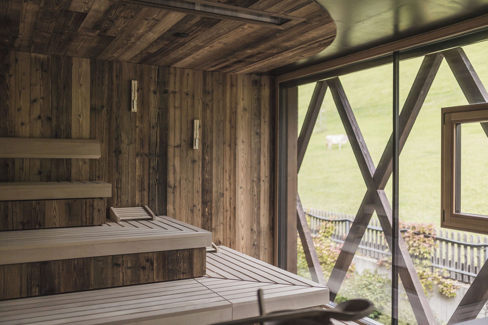 A wooden interior with a bench and a window with a geometric design.