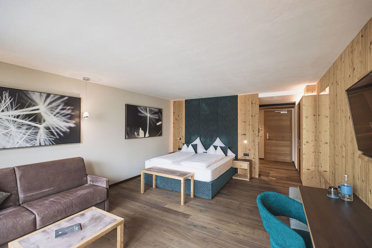 Een moderne hotelkamer met een bed, een bank, een eettafeltje en een stoel.