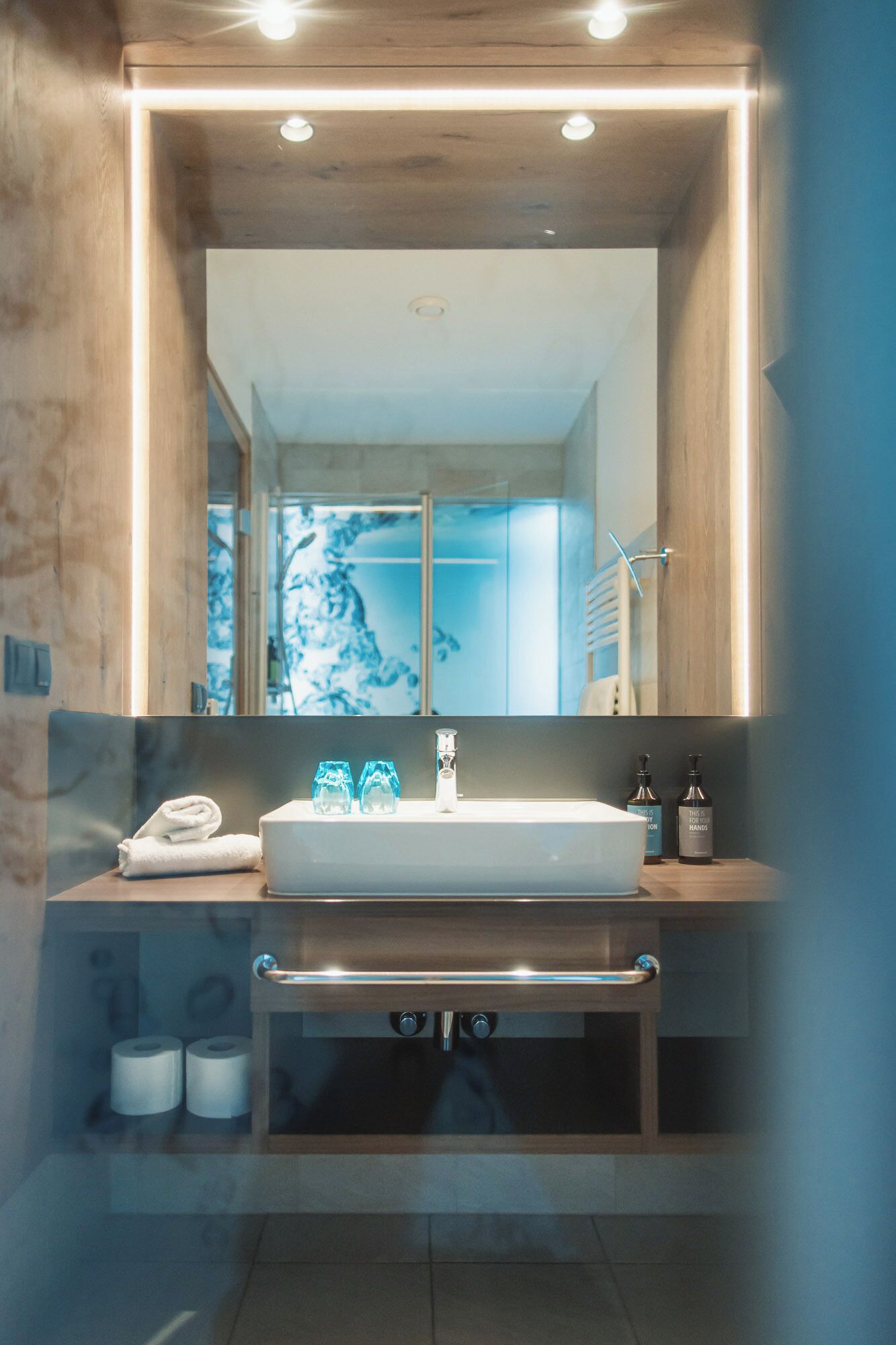 Un baño moderno con un espejo grande, un lavabo y un perchero para toallas.
