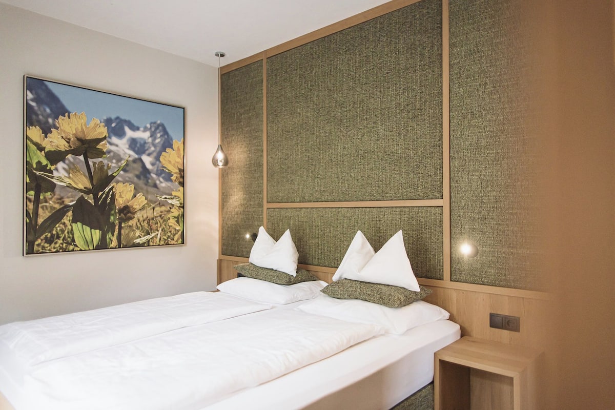 Een hotelkamer met een groot bed, een bloemen schilderij en een textuur wandpaneel.