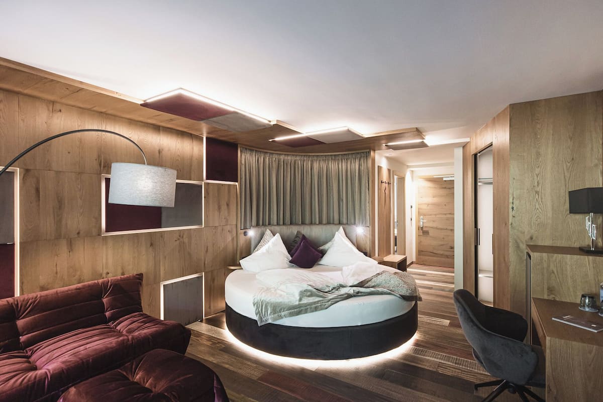 Een moderne hotelkamer met een rond bed, een bureau en een zithoek.