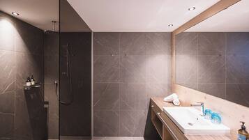 A modern bathroom with a glass-enclosed shower, a wooden vanity with a sink, and a large mirror.