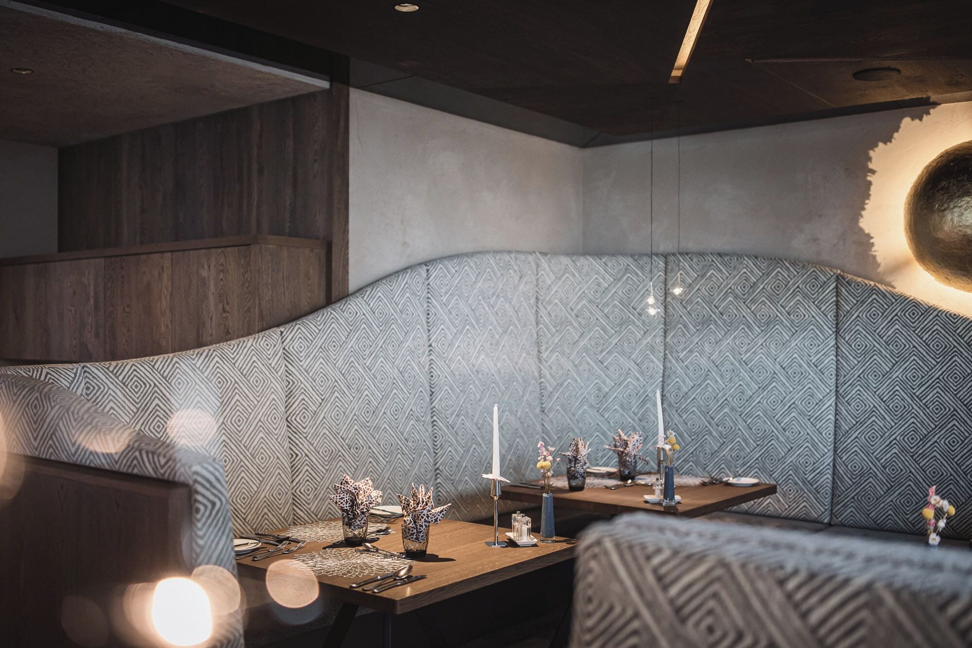 Un comedor moderno con pared estampada, una mesa de madera dispuesta para una comida y un diseño de techo original.