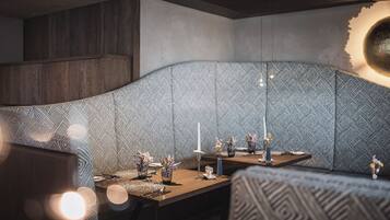 Un comedor moderno con pared estampada, una mesa de madera dispuesta para una comida y un diseño de techo original.