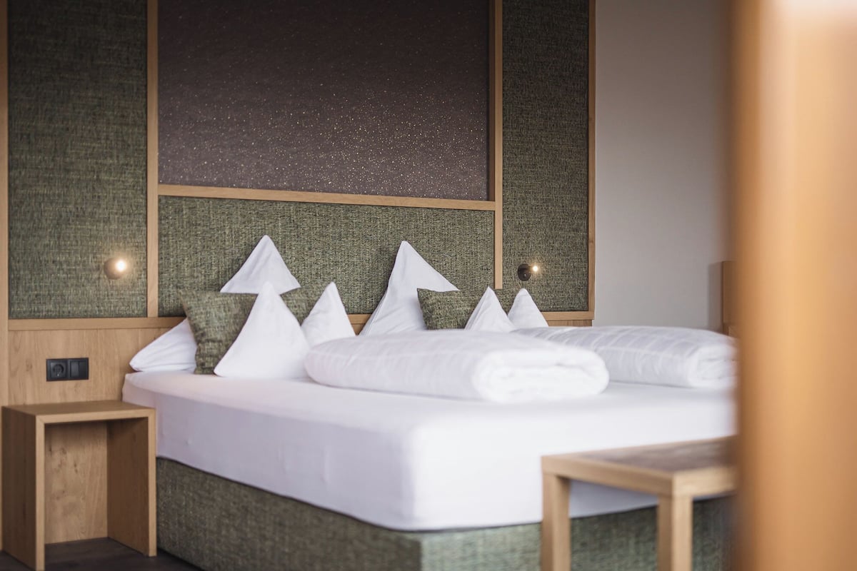 Een keurig opgemaakt bed met witte lakens en decoratieve kussens in een moderne hotelkamer.