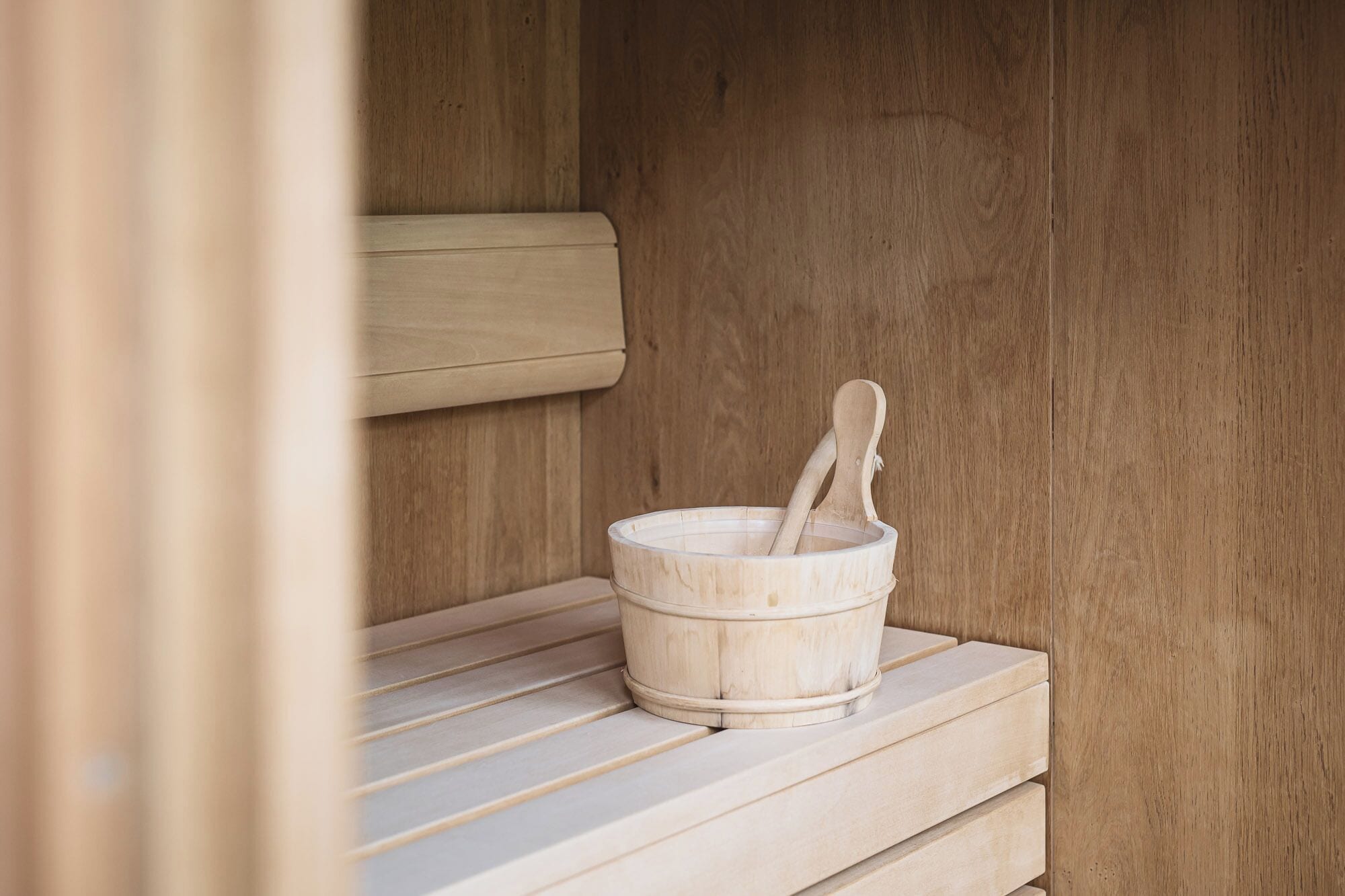 A wooden sauna with a wooden bucket and a wooden spoon.