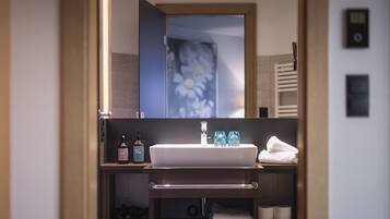 A bathroom with a white sink, a mirror, and a towel rack. There are two bottles of lotion on the shelf.
