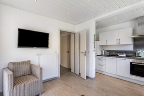 A modern kitchen with white cabinets, a built-in oven, and a flat-screen TV mounted on the wall. - Apartment 'Typ 3' with Shared Garden, Balcony and Wi-Fi (Willingen (Upland))