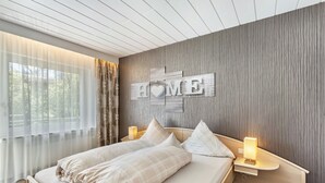 Una habitación de hotel moderna con una cama grande, lámparas de noche y un cartel con la palabra 'HOME'.