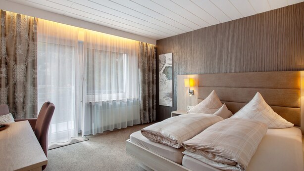 Quarto de hotel com uma cama, uma mesa e uma cadeira.