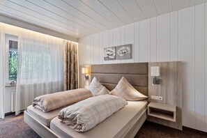 A hotel room with a bed, a nightstand, a lamp, and a window with curtains. - Apartment 'Typ 5' with Shared Garden, Balcony and Wi-Fi (Willingen (Upland))