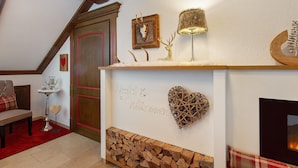 A room with a fireplace, a wooden mantel, a red heart-shaped decoration, and a welcome sign.