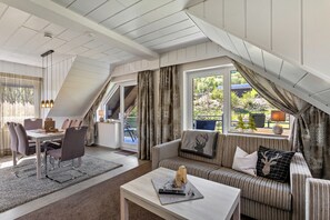 A cozy loft-style room with a dining area, a sofa, and a window with curtains. - Apartment 'Typ 5' with Shared Garden, Balcony and Wi-Fi (Willingen (Upland))