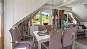 A dining area with a table, chairs, and a view of a garden through a window.