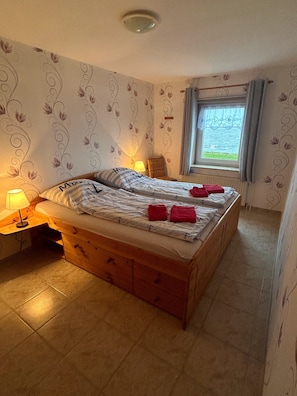 Ein Schlafzimmer mit einem Bett, zwei Nachttischlampen, einem Fenster mit Blick und einer Wand mit Muster.
