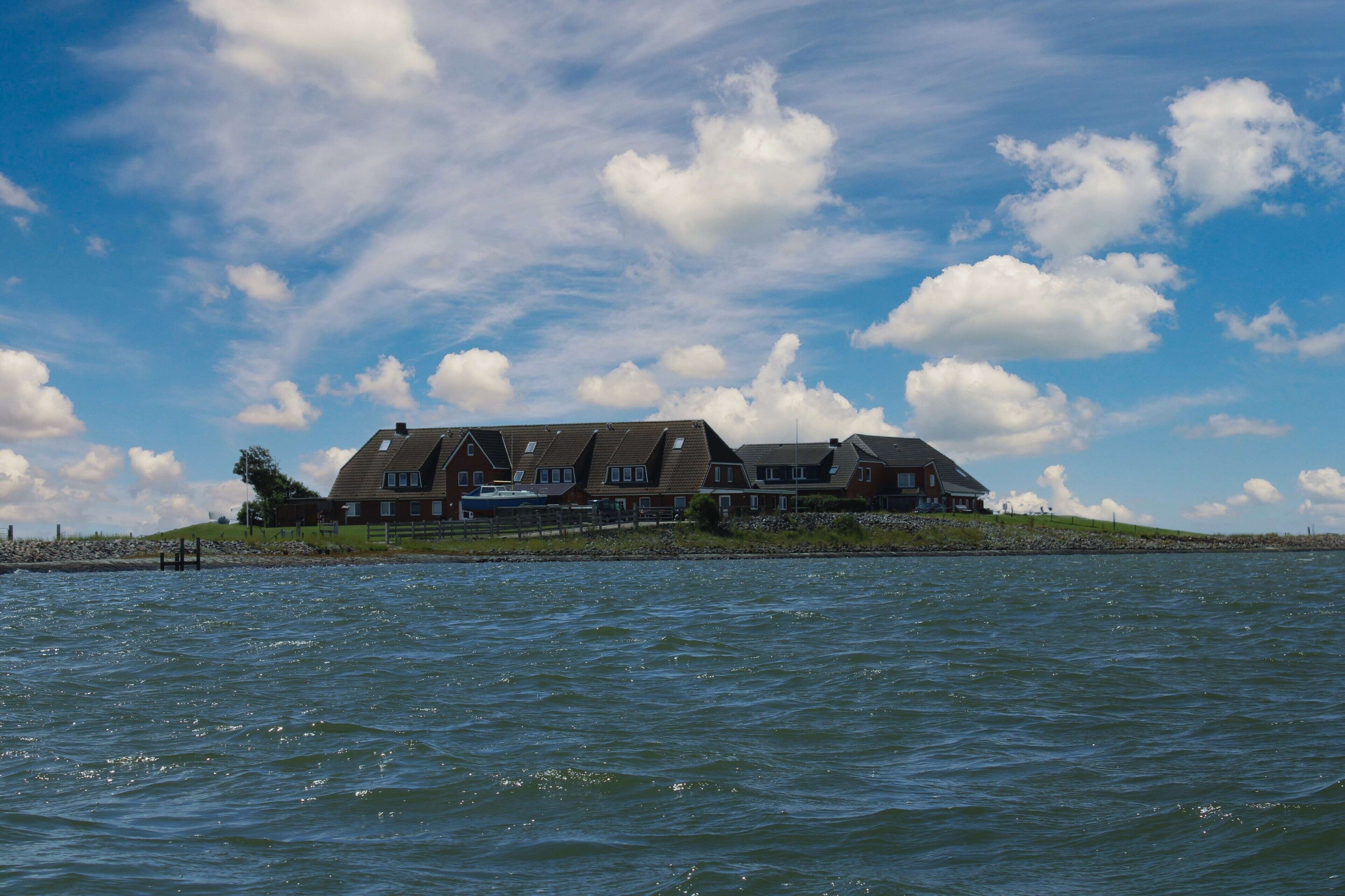 A large house by the water with a clear sky.