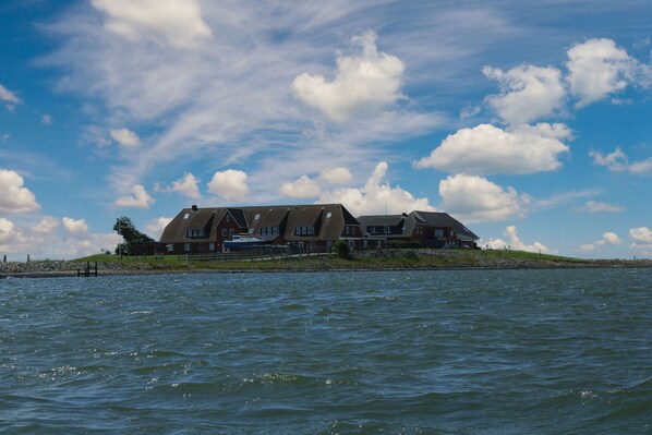 A large house by the water with a clear sky.