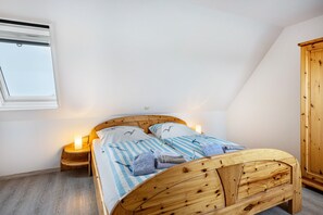 Quarto com cama de madeira, mesa de cabeceira, guarda-roupa e janela.