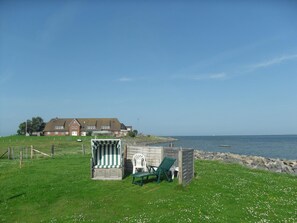 A beachside property with a small wooden structure, a chair, and a building in the background.