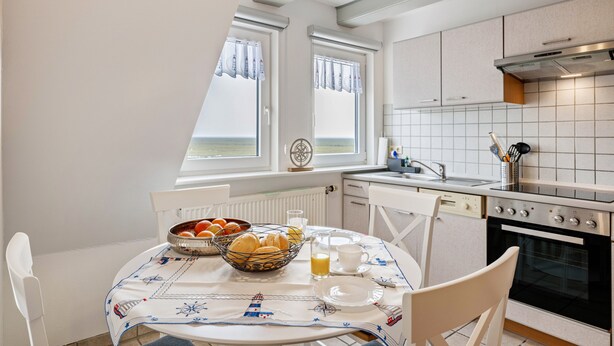 Eine Küche mit Esstisch, gedeckt für das Frühstück, einer Obstschale und einer Kaffeetasse.