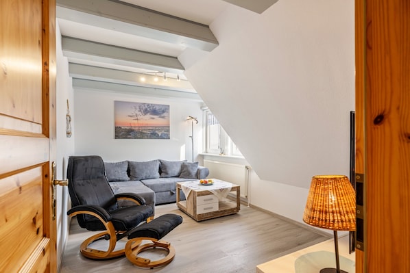 Un salon moderne avec un canapé, un fauteuil à bascule, une table basse et une lampe.