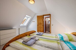 Une chambre avec deux lits, une lucarne, une porte en bois et une vue sur la salle de bain.