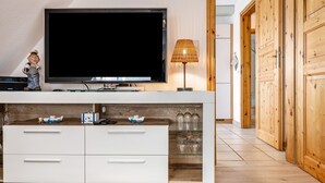 Ein modernes Wohnzimmer mit Flachbildfernseher, einem Holzschrank und einer Lampe.