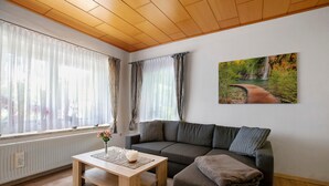 Una sala de estar con un sofá, una mesa de centro y un cuadro de un paisaje.