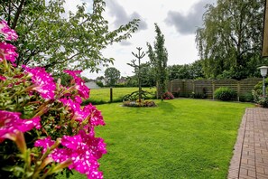 A well-maintained garden with a lawn, a wooden fence, and flowering plants.