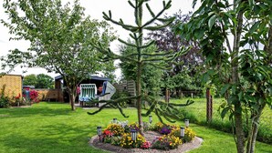 Un jardín bien cuidado con una variedad de flores y un pequeño árbol en el centro.