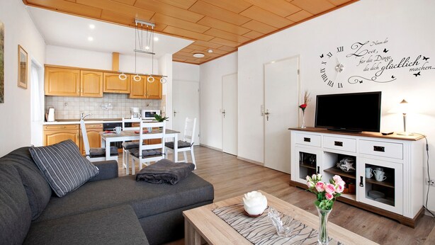 Una sala de estar moderna con un sofá, una mesa de centro y un mueble para televisión con un televisor de pantalla plana.