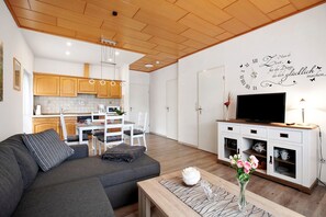 Een moderne woonkamer met een bank, een salontafel en een tv-meubel met een flatscreen-televisie.
